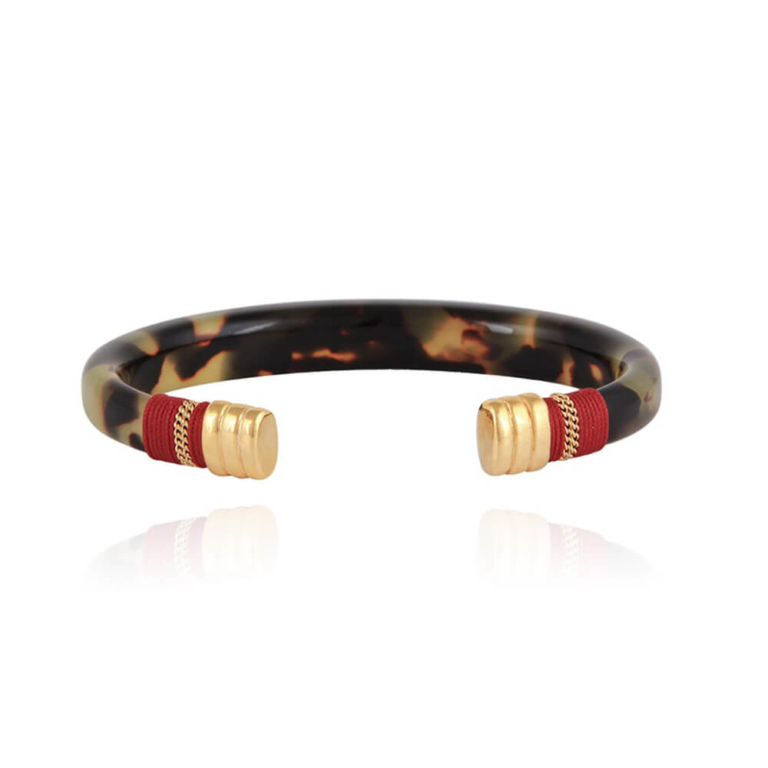 Pulsera abierta de acetato, con extremos bañados en oro de 24k y envuelta en hilo rojo.