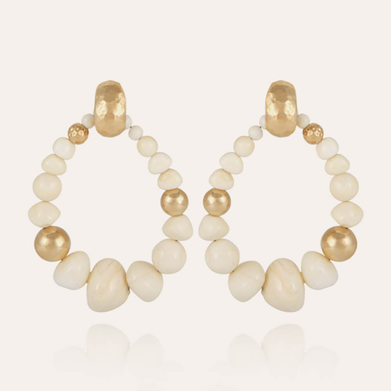 Pendientes compuestos por perlas de acetato y perlas doradas con oro fino, cuidadosamente ensambladas en forma de gota. Todas las cuentas de la composición son únicas y moldeadas individualmente. Están vestidos con un elegante broche martillado.