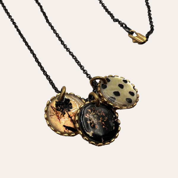 Este collar largo se hace a mano, utilizando un proceso de esmaltado en nácar tahitiano. Las ilustraciones esmaltadas provienen de antiguos documentos y tejidos acumulados a lo largo del tiempo, o simplemente nacidos de la imaginación.