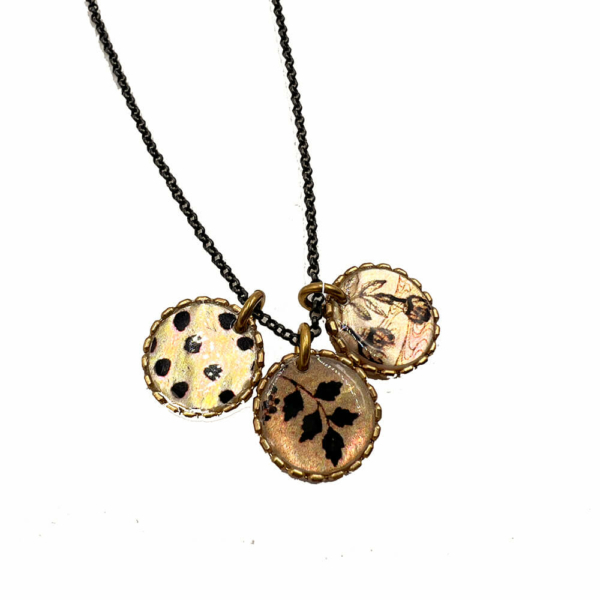 Este collar largo se hace a mano, utilizando un proceso de esmaltado en nácar tahitiano. Las ilustraciones esmaltadas provienen de antiguos documentos y tejidos acumulados a lo largo del tiempo, o simplemente nacidos de la imaginación.