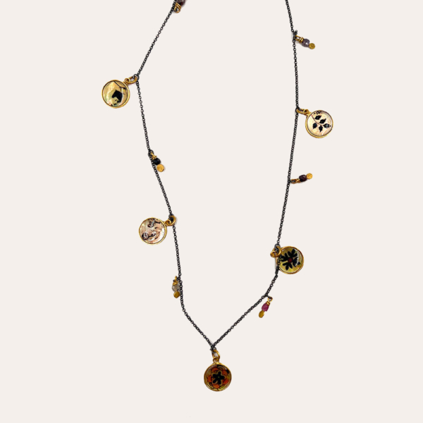 Este collar largo se hace a mano, utilizando un proceso de esmaltado en nácar tahitiano. Las ilustraciones esmaltadas provienen de antiguos documentos y tejidos acumulados a lo largo del tiempo, o simplemente nacidos de la imaginación.